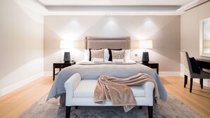 A modern bedroom with a large bed, two bedside tables, a desk, and a chair.