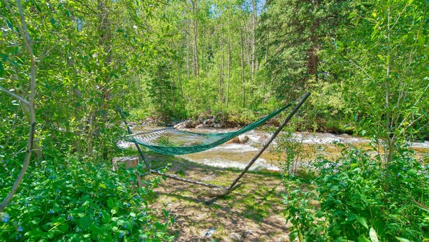 A hammock in a forested area with a stream. - Rustic Riverside Cabin with Patio — Family Escape (Lyons)