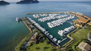 Luchtbeeld van een jachthaven met tal van boten die aangemeerd liggen, omgeven door een kustlandschap en woongebouwen.