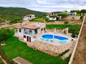 Residential property with a Mediterranean-style pool and lush greenery, set on a hillside with scenic views.