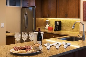 A kitchen with a granite countertop, stainless steel appliances, and wooden cabinets. - Oceanfront Mahana Condo  1BR/1BA Sweeping Views Ac, Pool (Lahaina)