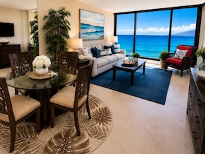 A living room with a dining area, a sofa, a coffee table, and a view of the ocean.