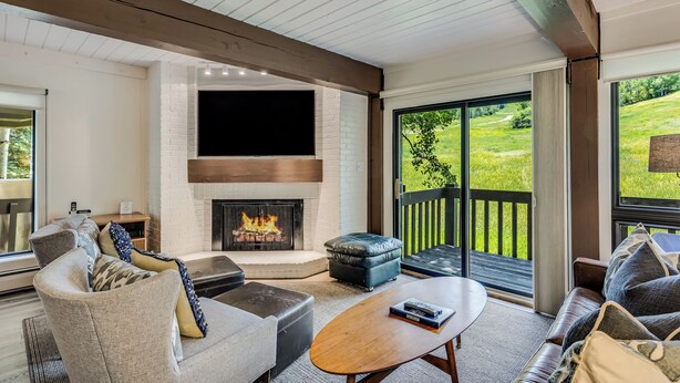 A modern living room with a fireplace, comfortable seating, and large windows offering a view of the outdoors. - 🏔️Incredible Mtn Views & Ski Access~Hot Tub~Interlude 204🏔️ (Snowmass Village)