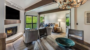 A cozy living room with a fireplace, comfortable seating, and a large window. - 🏔️Incredible Mtn Views & Ski Access~Hot Tub~Interlude 204🏔️ (Snowmass Village)