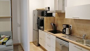 Une cuisine compacte équipée d’un réfrigérateur, d’un four à micro-ondes, d’une cuisinière, d’un évier et d’une machine à café.