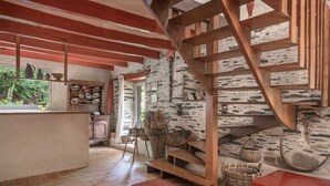Una cucina rustica con una scala in legno, un muro in pietra e una finestra che si affaccia sul verde.