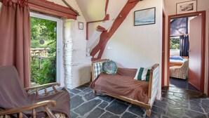 Una camera accogliente con un letto, una poltrona a dondolo e una finestra con vista sul verde.