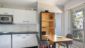 A modern kitchen with white cabinets, a microwave, and a wooden dining table with chairs. - Apartment for 2 adults/2 kids, balcony (La Baule-Escoublac)