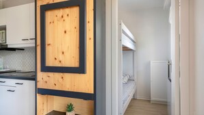 A modern kitchen with white cabinets, a wooden accent wall, and a small plant on a black shelf. - Apartment for 2 adults/2 kids, balcony (La Baule-Escoublac)