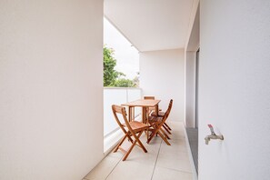 A small balcony with a wooden table and chairs, a window, and a water tap. - Relax in this beautiful flat in Lacanau (Lacanau)