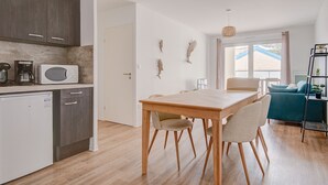 A modern kitchen with a microwave, coffee maker, and dishwasher. There is a dining area with a wooden table and chairs. - Relax in this beautiful flat in Lacanau (Lacanau)