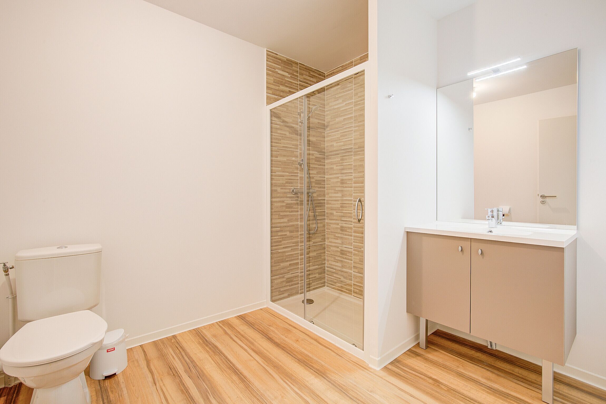 Un baño con inodoro, ducha envuelta en vidrio y tocador con espejo.