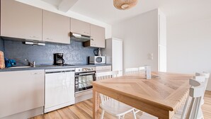 A modern kitchen with white cabinetry, a wooden dining table, and white chairs.