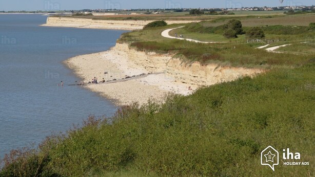 Un paysage côtier avec une plage de sable, des zones herbeuses et un ciel dégagé.