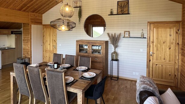 Un coin repas avec une table en bois dressée pour quatre personnes, entourée de chaises, et agrémenté d’un buffet en bois et d’un miroir au-dessus.