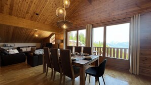 Un chalet en bois chaleureux comprenant un coin repas, un salon et un balcon offrant une vue sur la montagne.