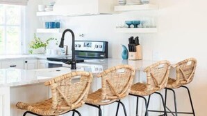 A modern kitchen with a central island, bar stools, and pendant lighting. - Luxury Nantucket Estate | Heated Pool & Hot Tub (Nantucket)