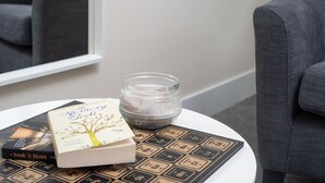 Un livre intitulé « Le livre de la mémoire » est posé sur une table blanche, accompagné d’une bougie et d’un dessous de verre.