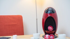 Une machine à café rouge avec une tasse de café posée sur une table.