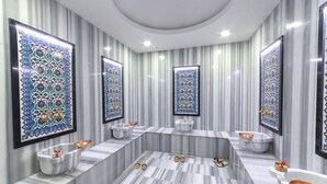 Un baño lujoso con tocador de mármol, una bañera independiente y un espejo grande con detalles de azulejos decorativos.