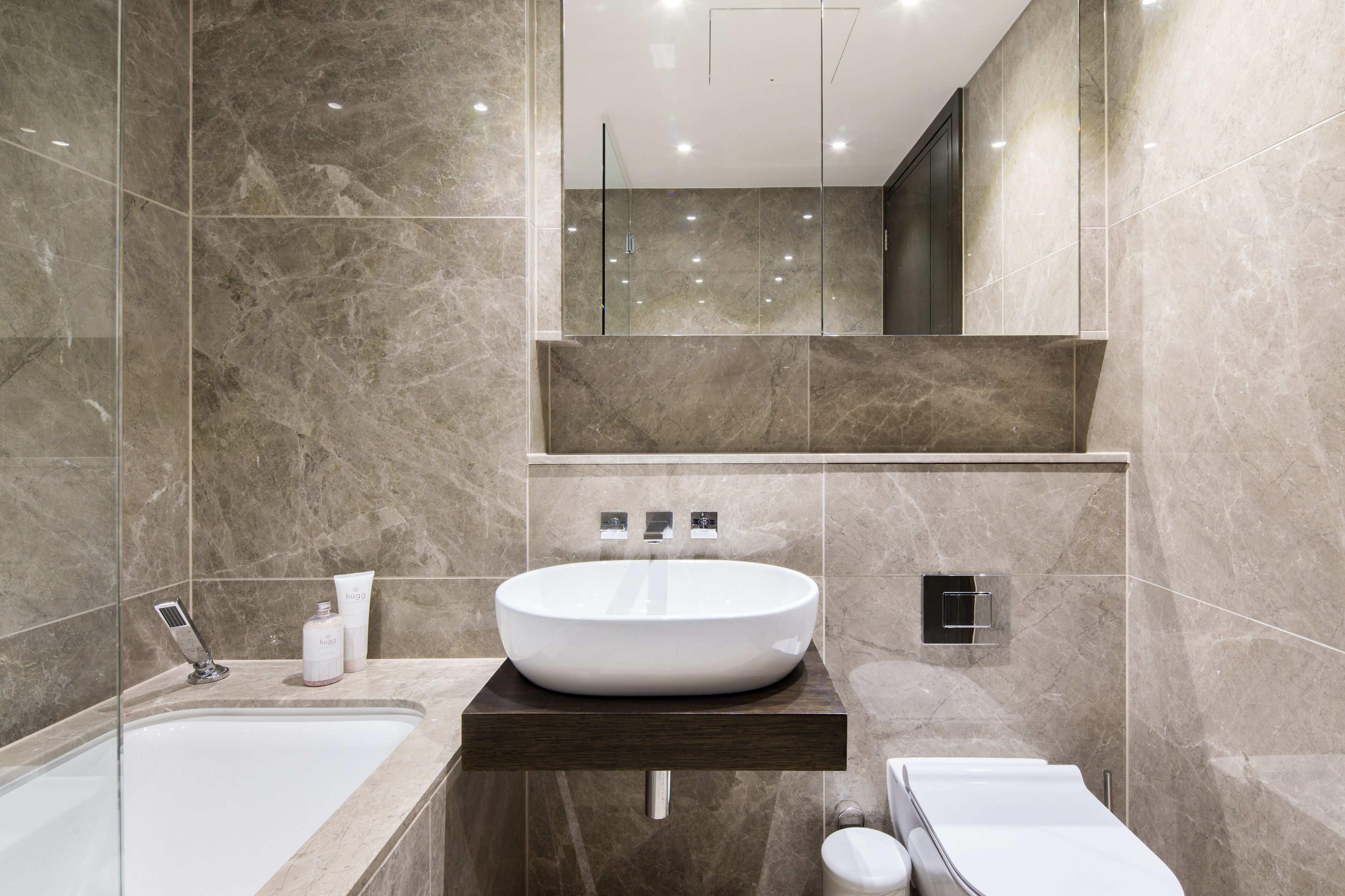 A modern bathroom with a large oval sink, a separate shower area, and a toilet.