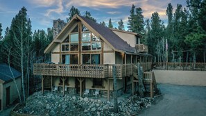 A two-story lodge with a balcony, wooden deck, and stone foundation.