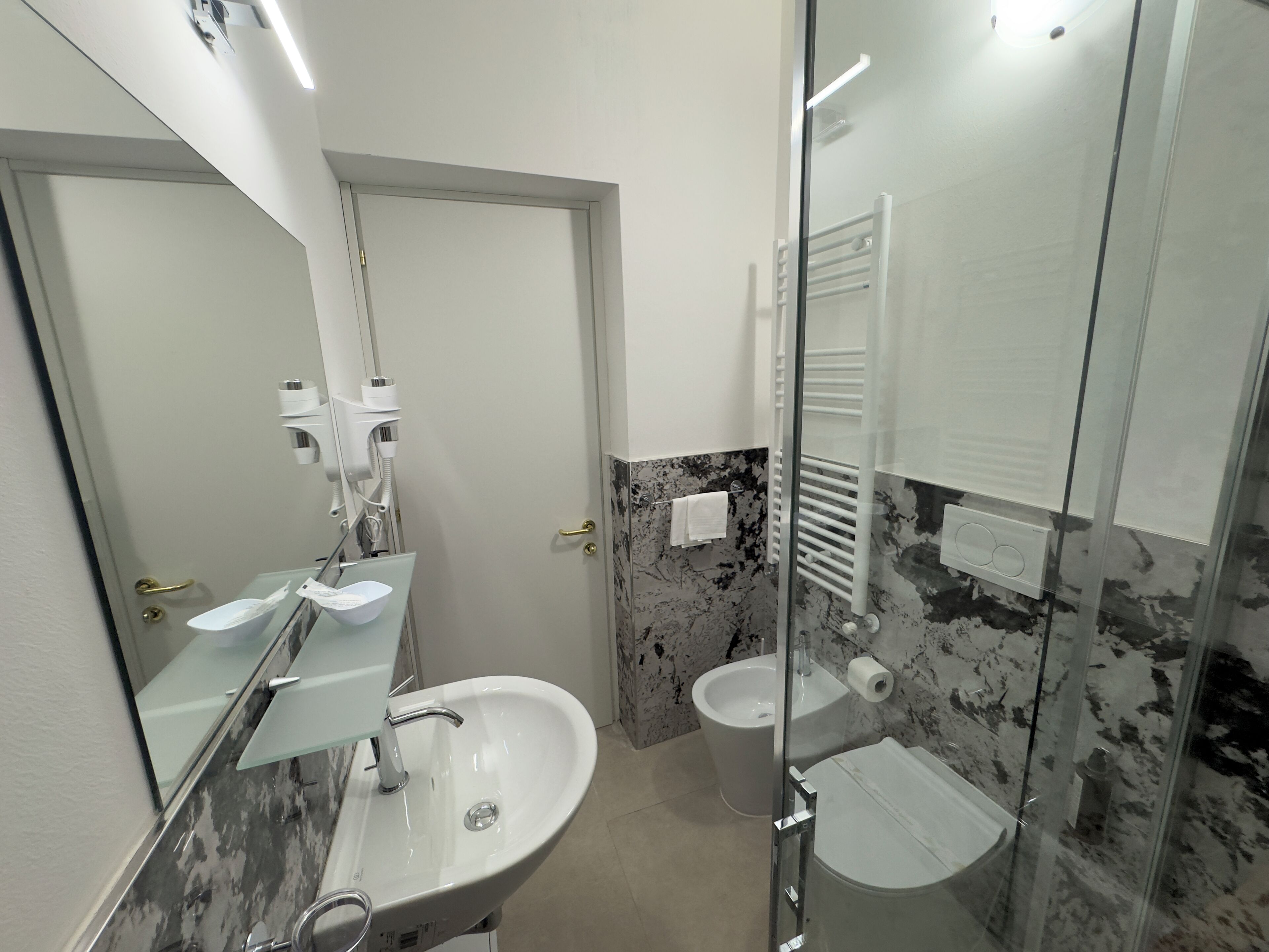 A modern bathroom with a glass shower enclosure, a white sink, and a toilet.