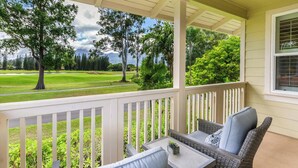 Une véranda meublée de meubles en osier, avec vue sur un terrain de golf.