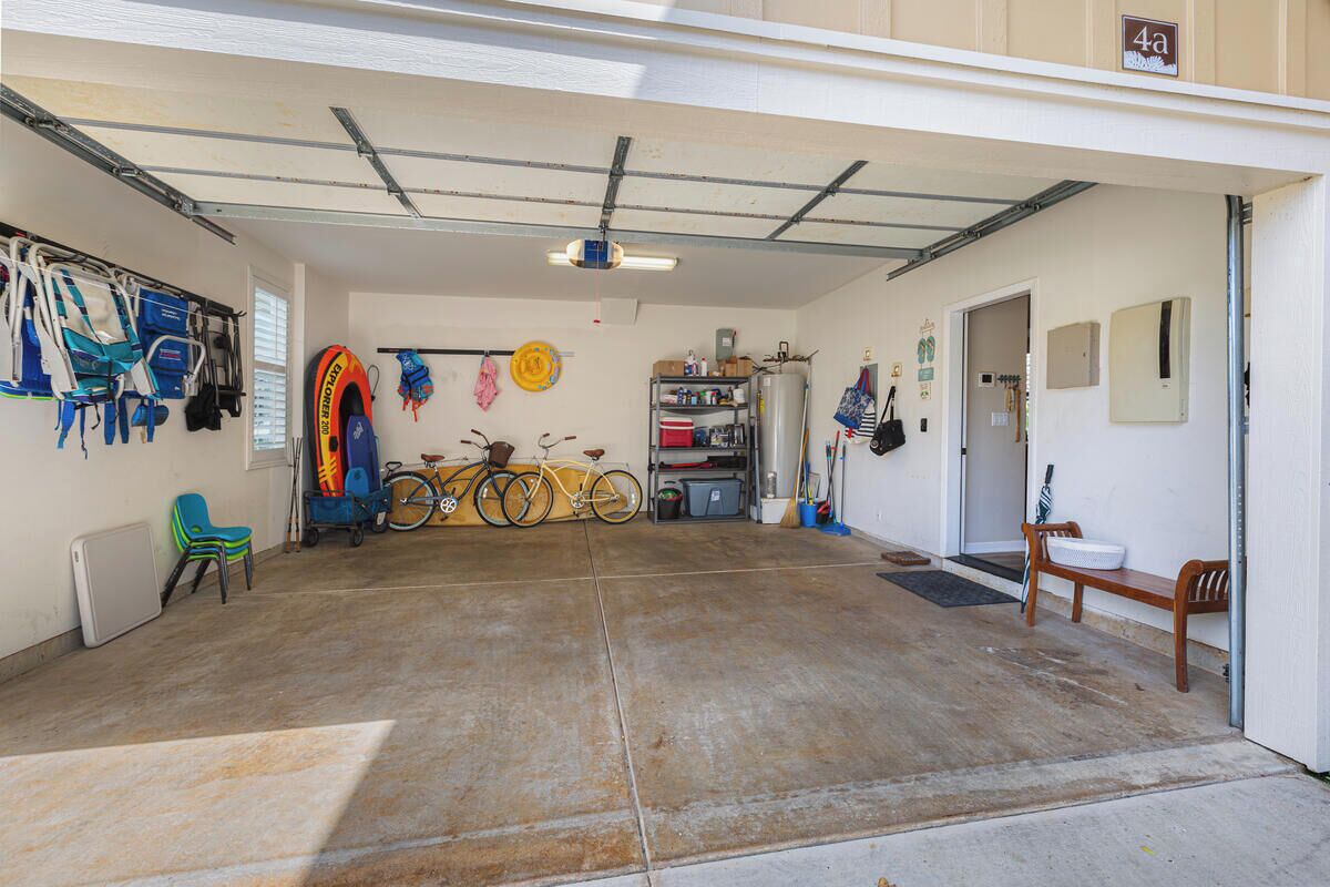 Un garage contenant des vélos, un vélo jaune, une chaise blanche et une chaise bleue.