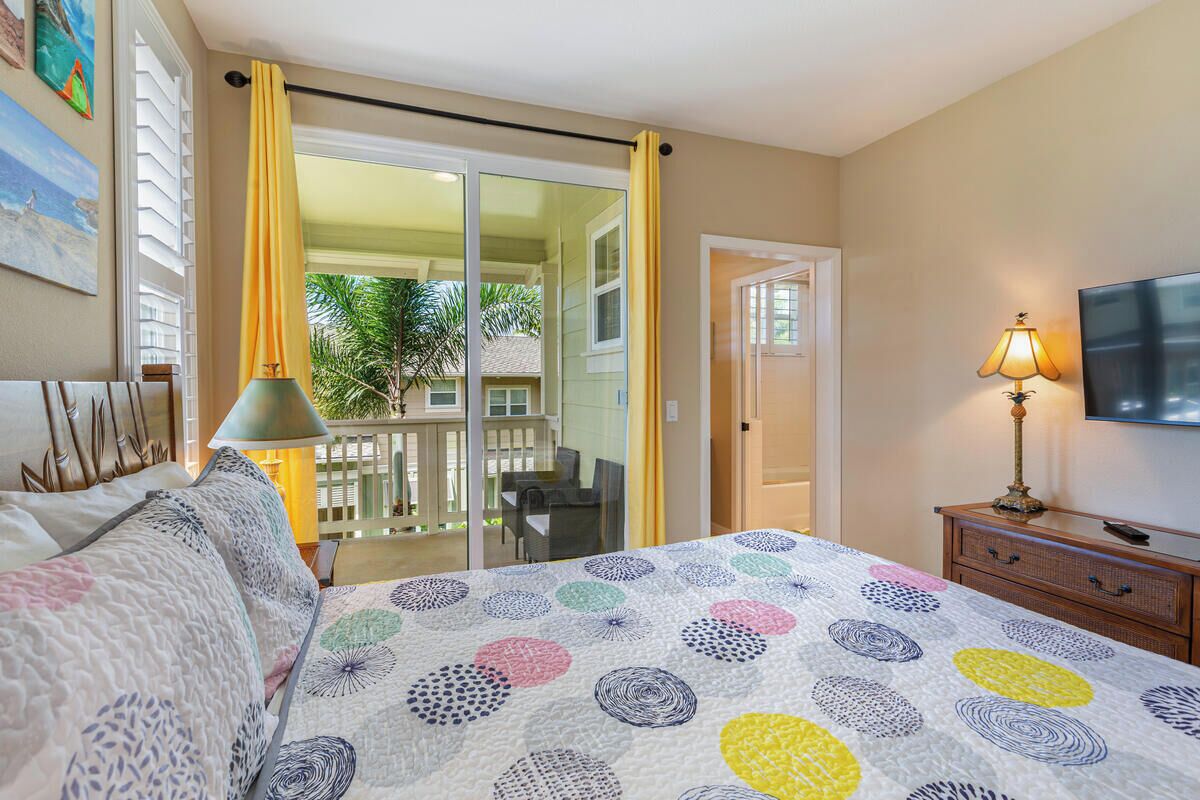 Ein Hotelzimmer mit Bett, Fernseher, Lampe und einem Balkon mit Blick ins Freie.