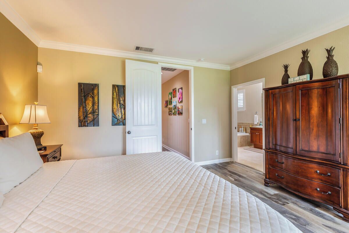 Une chambre à coucher avec un grand lit, une armoire en bois et une porte donnant sur une autre pièce.