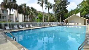 Una piscina con un indicador de profundidad de 2.4 metros, rodeada de palmeras y una cerca blanca.