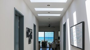 En modern hall med takfönster som leder vidare till ett matområde med utsikt över havet.