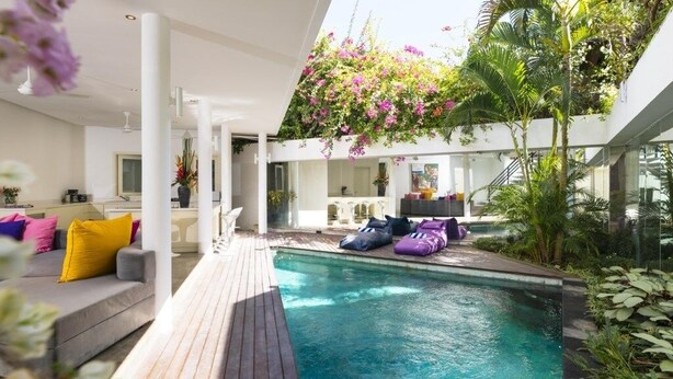 A modern pool area with a wooden deck, lounge chairs, and a variety of plants. - Villa La Sirena 2 Minutes From Beach 3 Bedroom Villa by RedAwning (Seminyak)