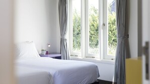 A bedroom with a bed, a nightstand, a lamp, and a window with curtains. - Villa La Sirena 2 Minutes From Beach 3 Bedroom Villa by RedAwning (Seminyak)