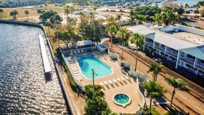 Un resort con piscina, palmeras y un puerto deportivo al fondo.