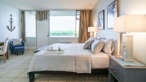 A bedroom with a bed, bedside table, lamp, and a view of the outdoors. - U409 SUN RISING- BALCONY WATERVIEW- SELF CHECK IN- PRIVATE BEACH RESORT (Ruskin)
