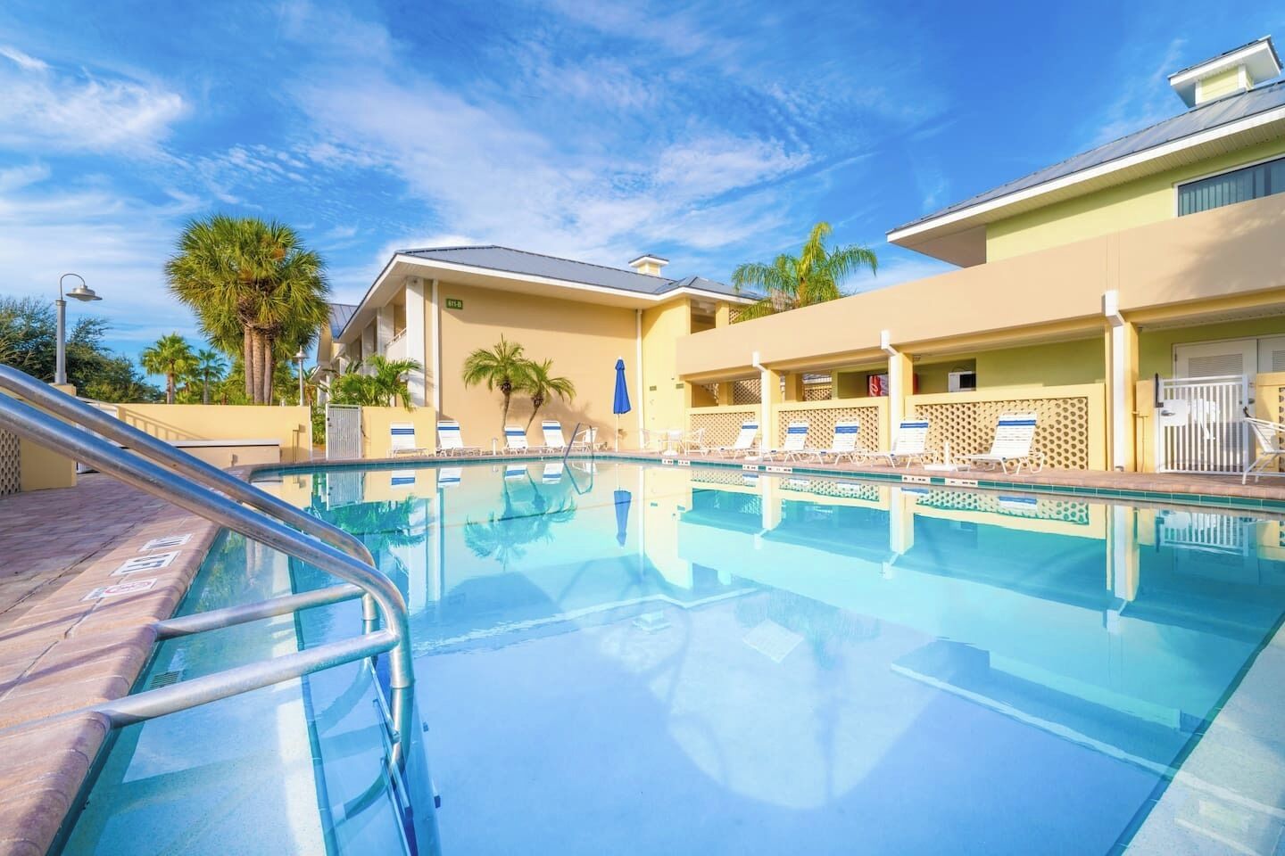 A swimming pool with lounge chairs and palm trees.