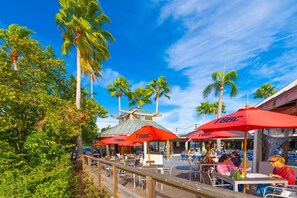 Guests can dine al fresco under the shade of our outdoor umbrellas, surrounded by lush greenery and palm trees.