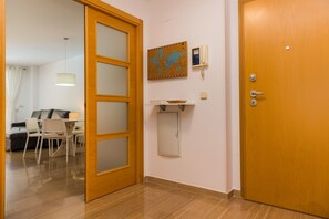 A room with a wooden door, a corkboard with a world map, a phone, and a small shelf. - Golden Gardens Saudade Apartment Javea Arenal (Javea / Xàbia)