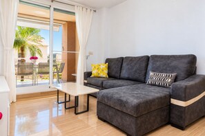 Een moderne woonkamer met een bank, een bijzettafeltje en uitzicht op het buitengebied.