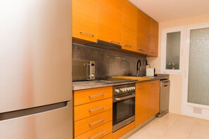 Una cocina moderna con armarios de madera, electrodomésticos de acero inoxidable y un salpicadero de azulejos.