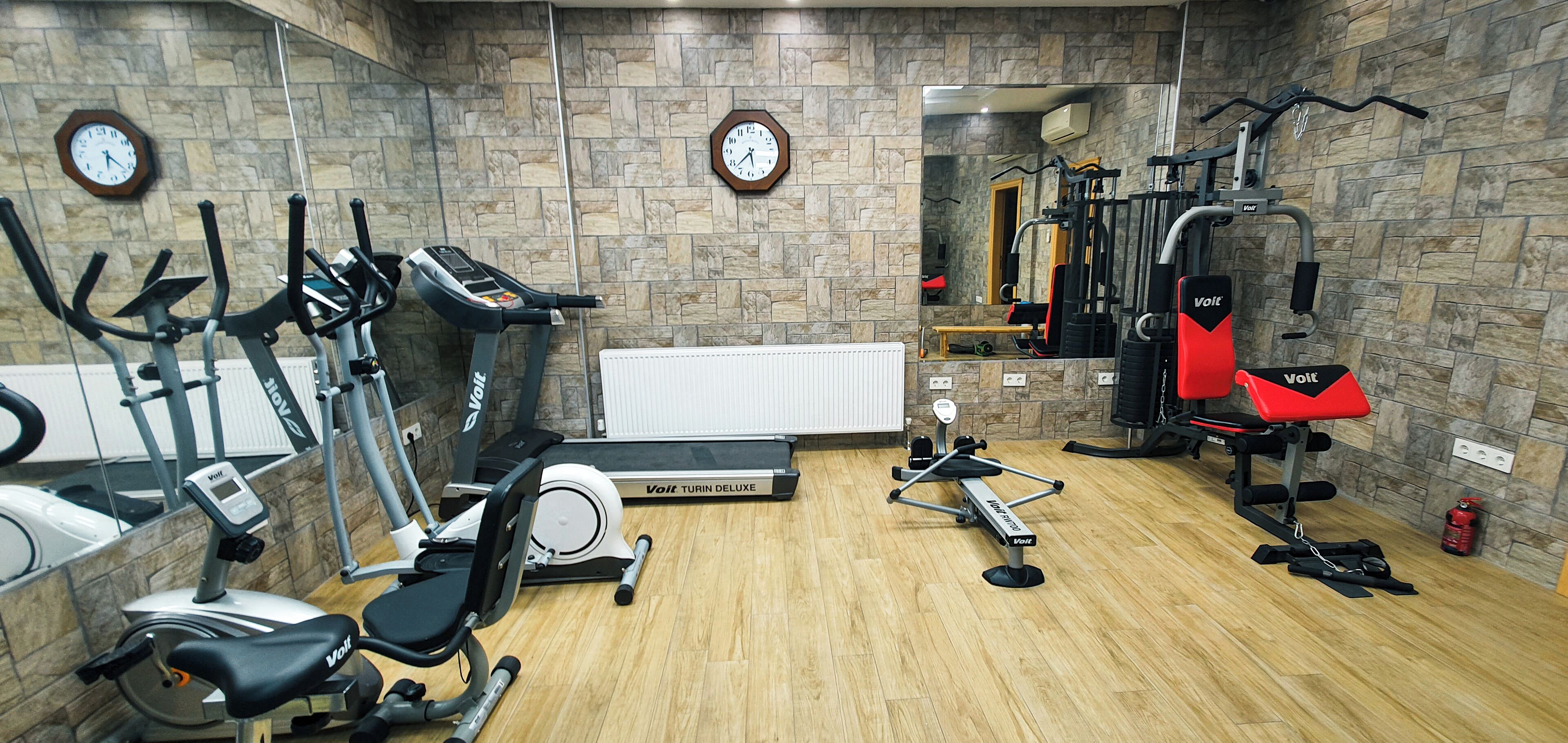 Ett gym med motionscyklar, löpband, roddmaskin och utrustning för styrketräning.