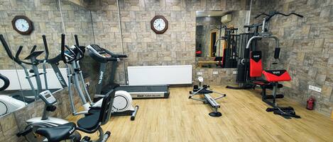Ett gym med motionscyklar, löpband, roddmaskin och utrustning för styrketräning.