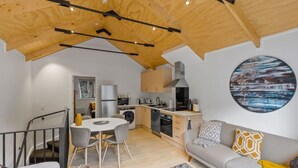 A modern kitchen with a dining area, a sofa, and a staircase. - Central Queenstown Apt 15a - with Gym walk to town (Queenstown)