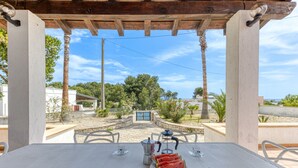A table set outdoors with a view of a garden and a blue gate. - Cozy house with pool 1km from sandy beach in Pescoluse (Pescoluse)