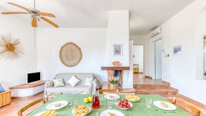 A dining area with a green tablecloth, a fireplace, and a ceiling fan. - Cozy house with pool 1km from sandy beach in Pescoluse (Pescoluse)