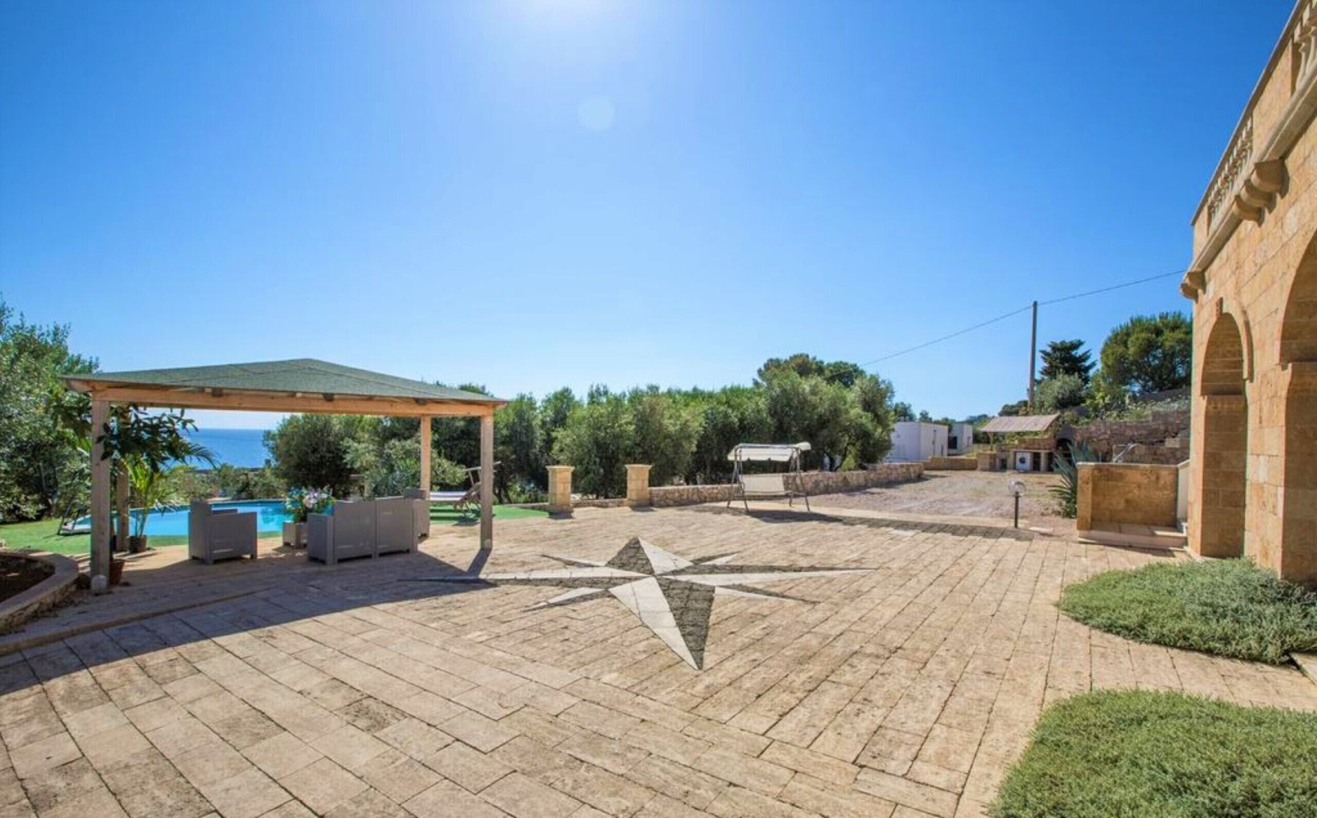 Um pátio com piscina, área de estar ao ar livre e pérgola.