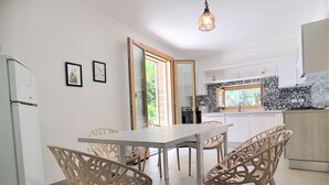 Una cocina moderna con armarios blancos, salpicadero de azulejos y una zona de comedor con mesa y sillas.