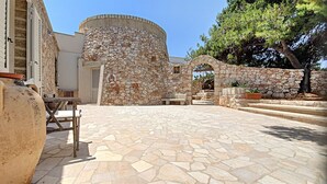 Un patio con suelo de piedra, una pared de piedra y un árbol.